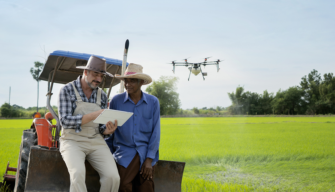 two men in broad-operate a drone while leaning on a golf cart