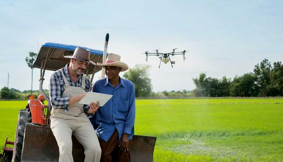 two men in broad-operate a drone while leaning on a golf cart