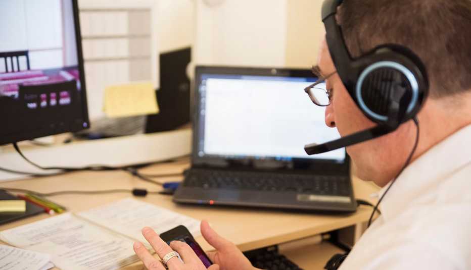 A man is looking at his phone with a headset on at a desk in his home