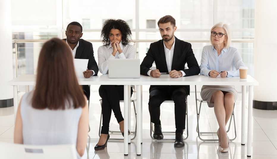A group of people sitting at a table interviewing a woman