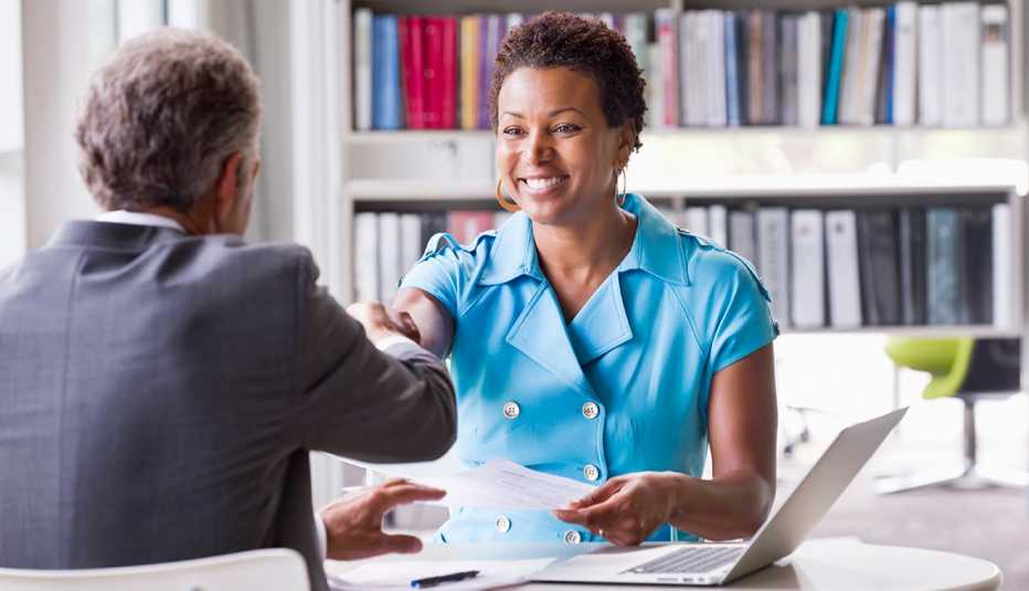 A woman and man shake hands at an office