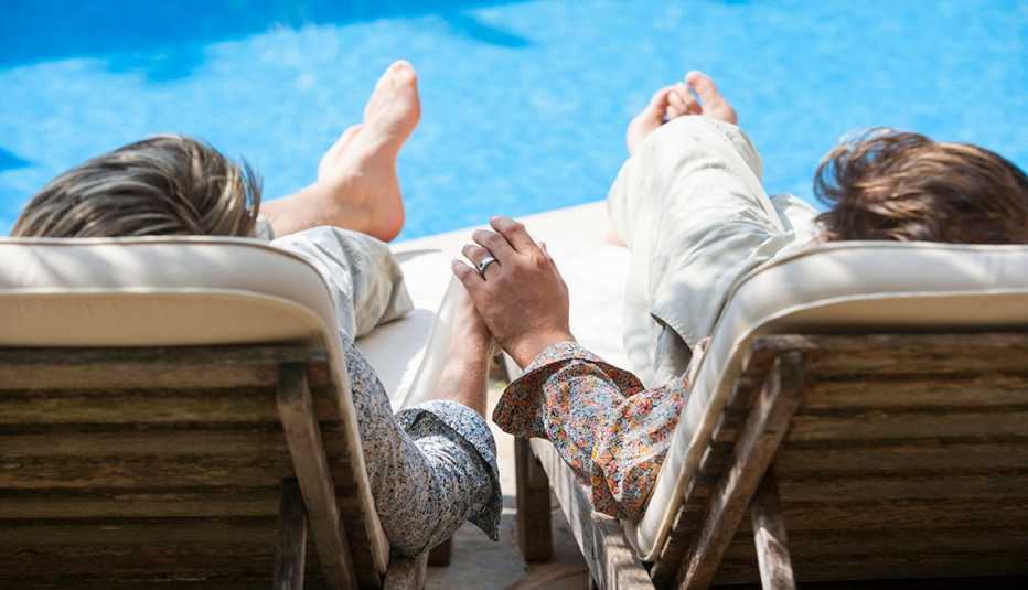 same sex couple sitting in pool chairs and holding hands