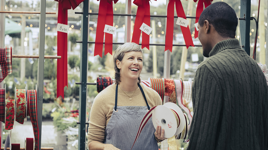 a seasonal worker at a wrapping station talks to a customer