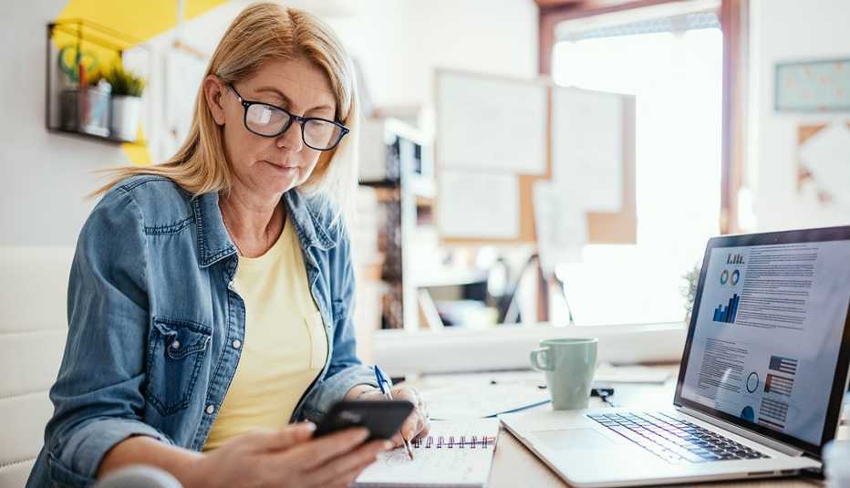 A woman looking at her phone while working at a desk
