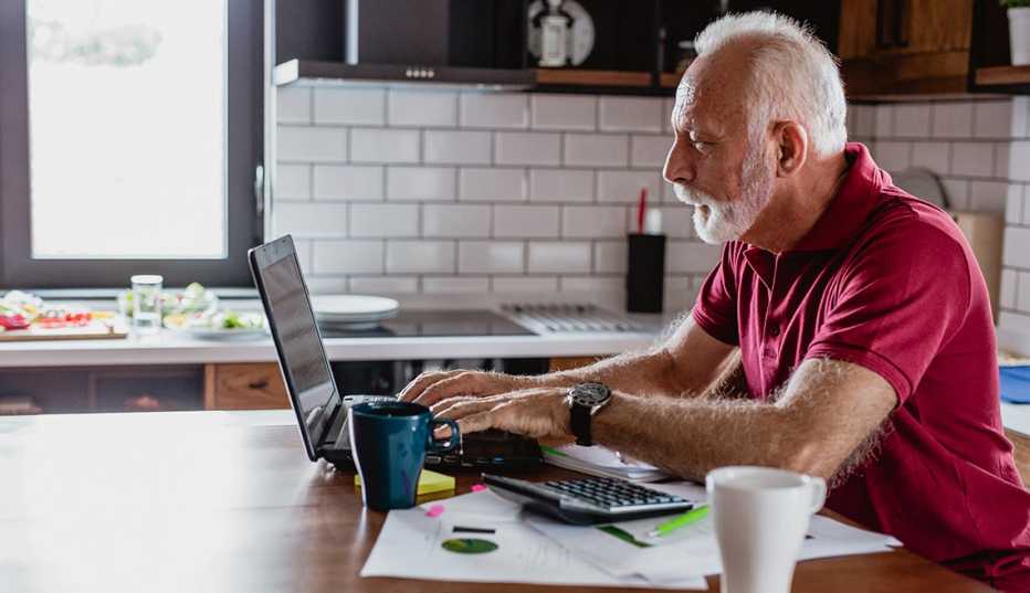 man works on laptop from his kitchen counter