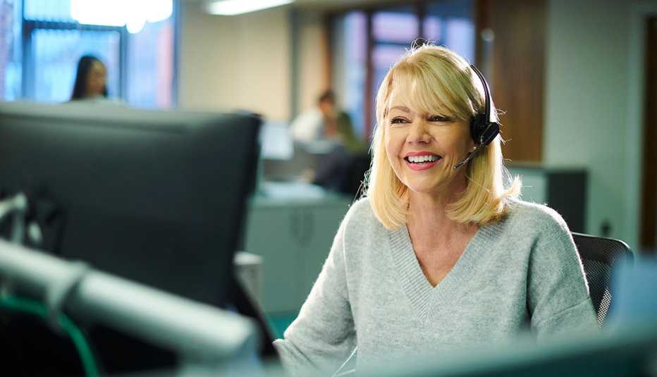 A woman talking on a headset while looking at a computer
