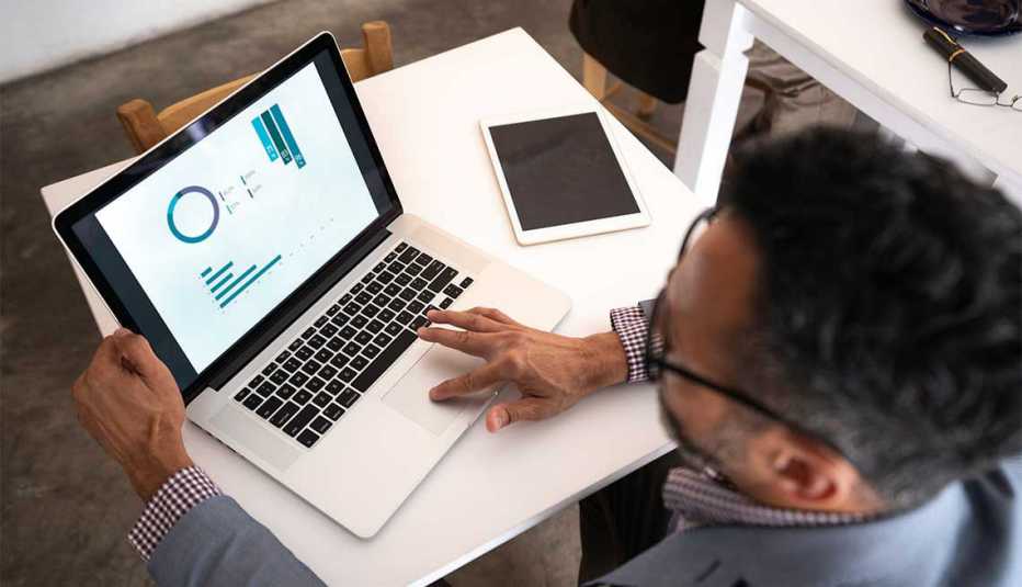A man sitting at a table looking at his laptop