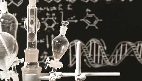 a black and white image showing chemistry equipment in front of a chalk board showing a formula a black and white image showing chemistry equipment in front of a chalk board showing a formula