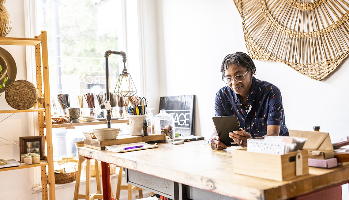 a business woman looks at a tablet device while leaning on a table in a workshop
