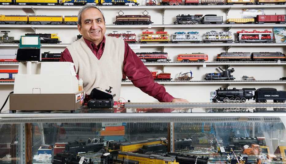a man in a vest stands behind a counter at a toy train hobby shop