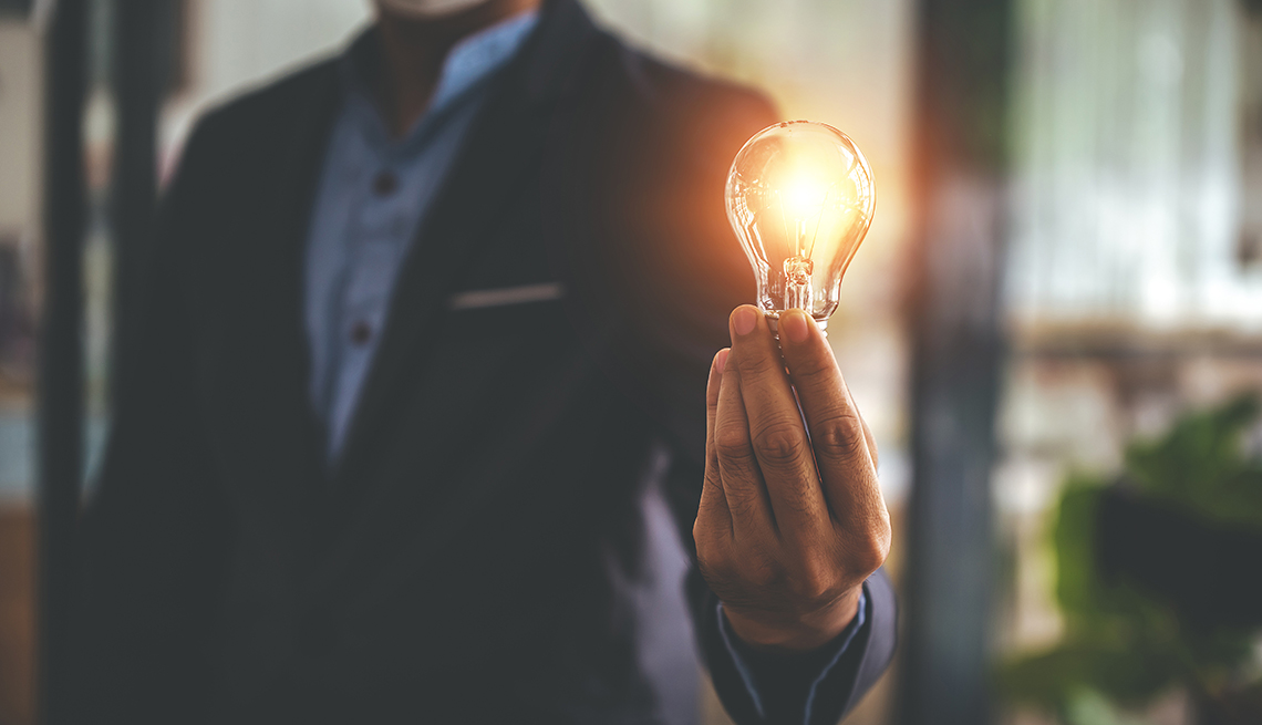 a man in a blazer holds a lightbulb