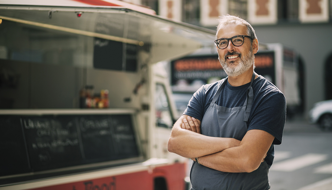man wearing apron standing in front of his food truck