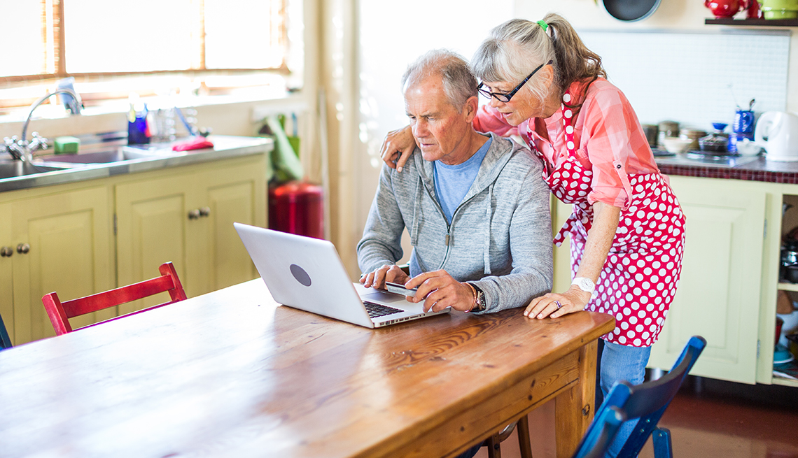 a couple sits at the table looking at a computer