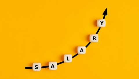 La palabra salary escrita en bloques de madera con un gráfico de flecha ascendente