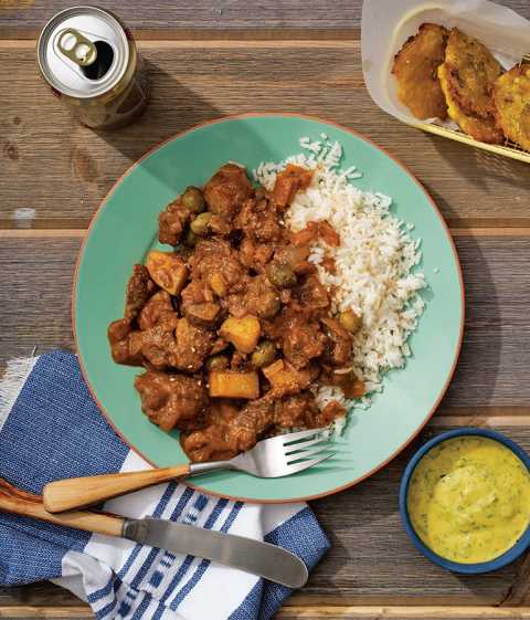 Plato servido con arroz blanco y carne guisada y salsa de mostaza y tostones por el lado Plato servido con arroz blanco y carne guisada y salsa de mostaza y tostones por el lado