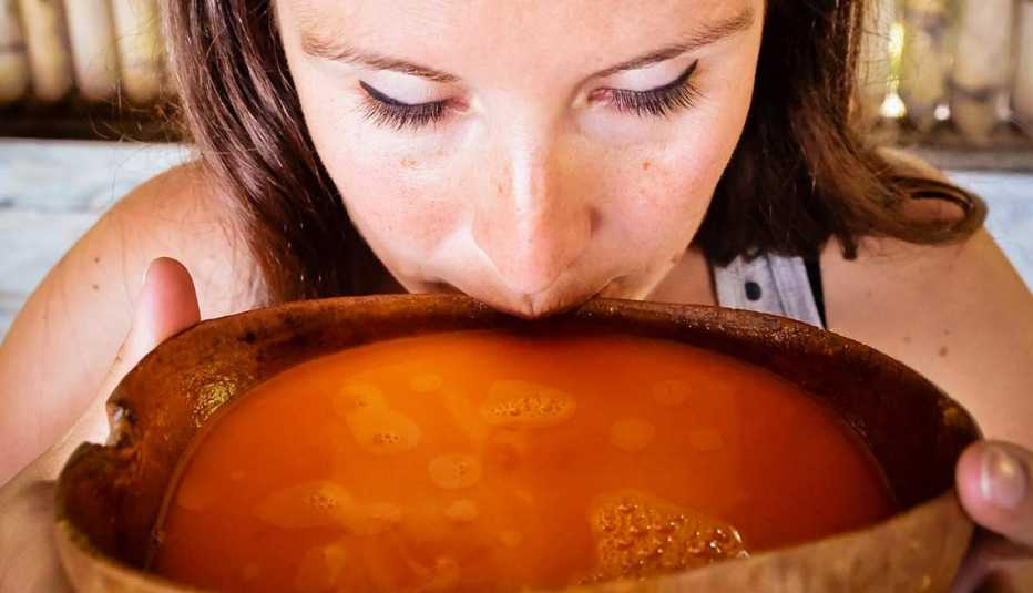 Mujer bebiendo chicha en un cuenco peruano tradicional