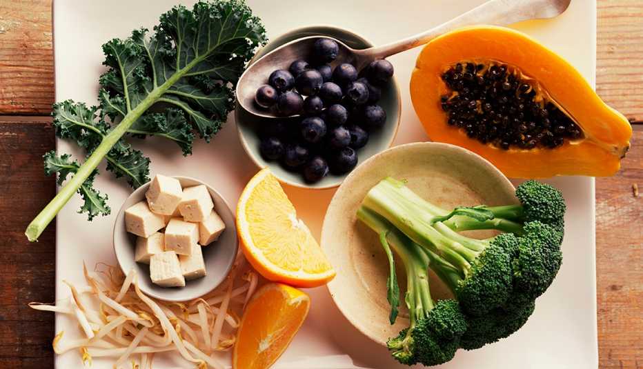Col rizada, brócoli, papaya, naranja y arándano sobre la mesa Col rizada, brócoli, papaya, naranja y arándano sobre la mesa