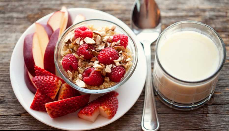 Un plato con fresas y frutos secos junto a un vaso de leche