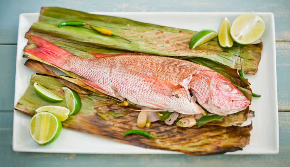 Pargo en una hoja de plátano y lima cortada en pedazos Pargo en una hoja de plátano y lima cortada en pedazos