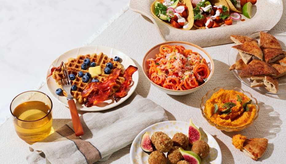Varios platos preparados usando zanahoria, entre ellos waffles, fideos, aderezo, salsa y hummus