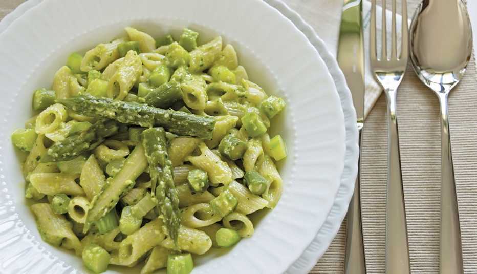 Pasta penne con una crema de espárragos servida en un plato blanco