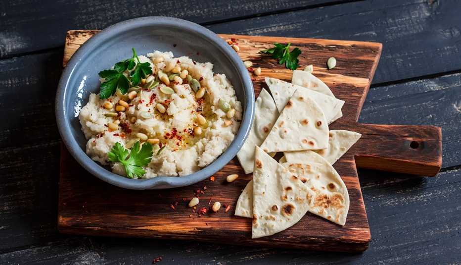 Hummus de coliflor servido sobre una tabla de madera