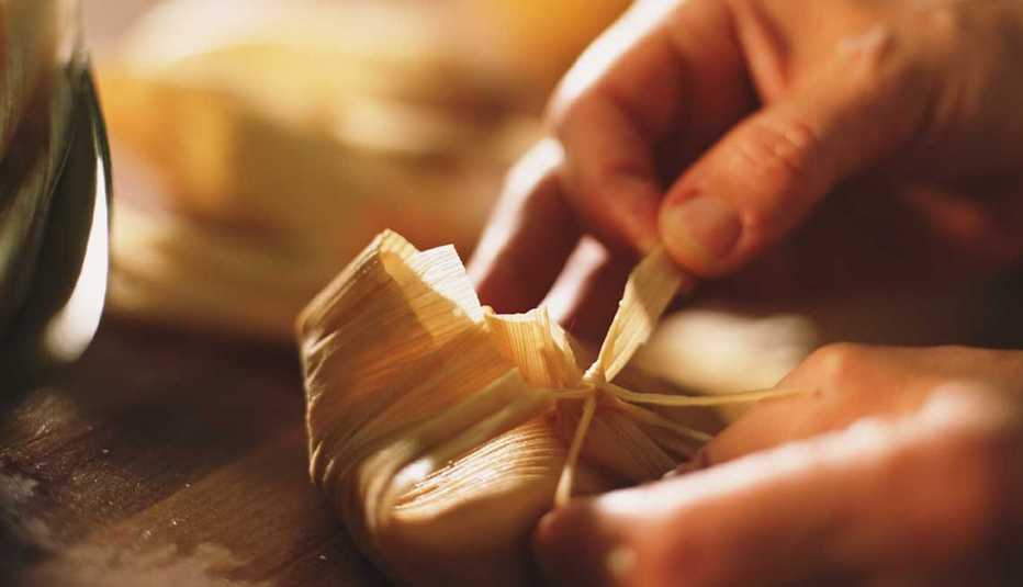 Manos de una persona envuelven un tamal Manos de una persona envuelven un tamal