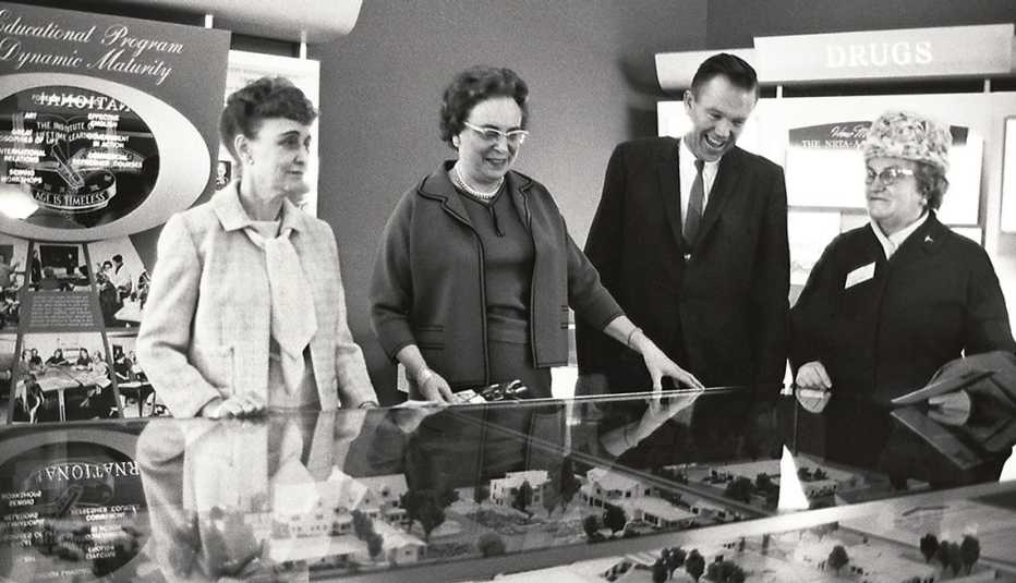 Tres mujeres y un hombre alrededor de un modelo conceptual del esquema de un desarrollo urbano.