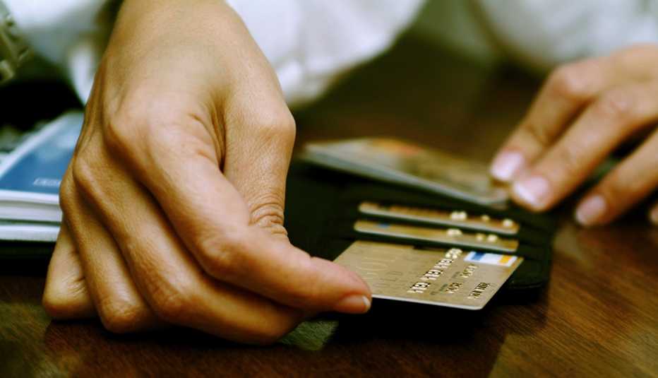 Manos sacando tarjetas de crédito de una billetera.