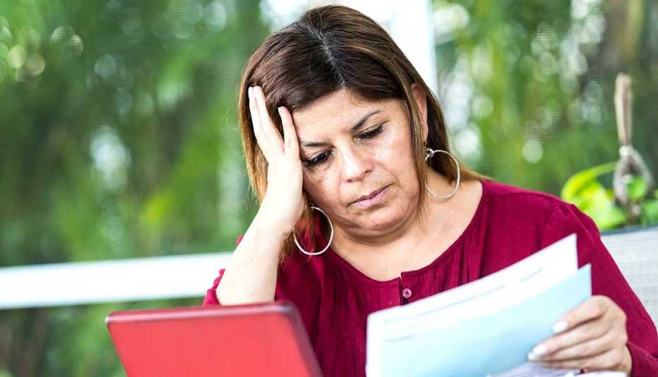 Mujer con documentos en la mano y una mano en la cabeza Mujer con documentos en la mano y una mano en la cabeza