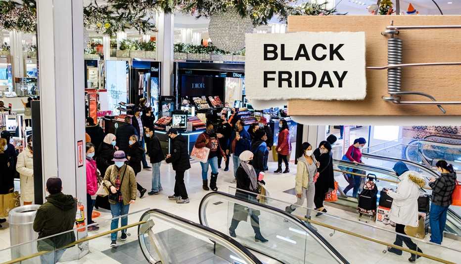 Personas en un centro comercial y un letrero en inglés que dice Viernes Negro