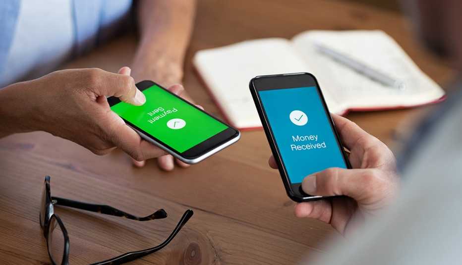 Un hombre y una mujer sostienen sus teléfonos inteligentes mientras hacen una transacción de pago electrónico Un hombre y una mujer sostienen sus teléfonos inteligentes mientras hacen una transacción de pago electrónico