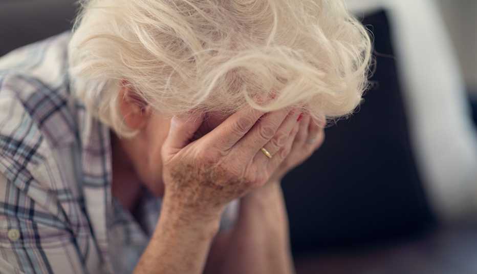 Mujer mayor sostiene su rostro en las manos
