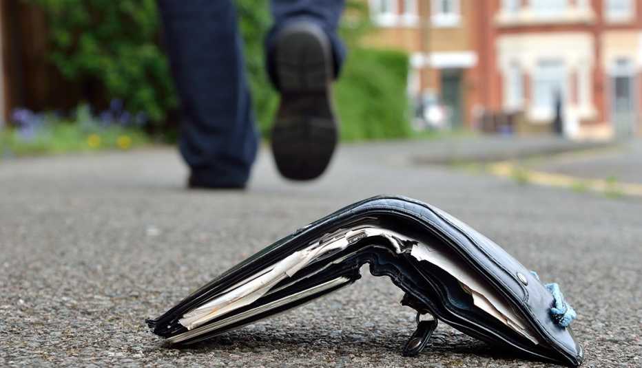 Billetera tirada en el suelo y los pies de un hombre alejándose.