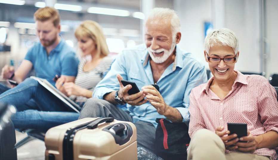 Grupo de personas usan sus aparatos electrónicos mientras esperan por un tren