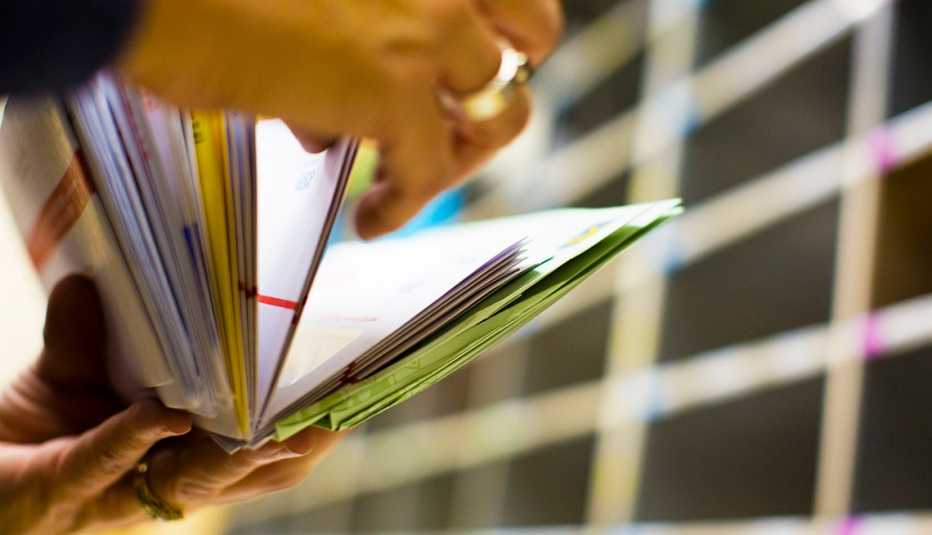 Manos de una persona organizando el correo en una oficina.