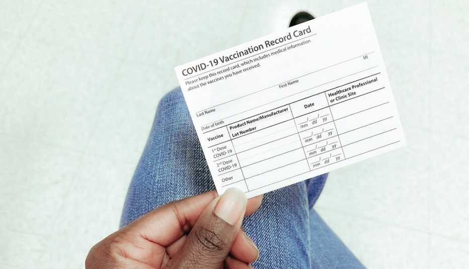 Manos de una mujer mostrando la tarjeta de vacunación de la COVID-19