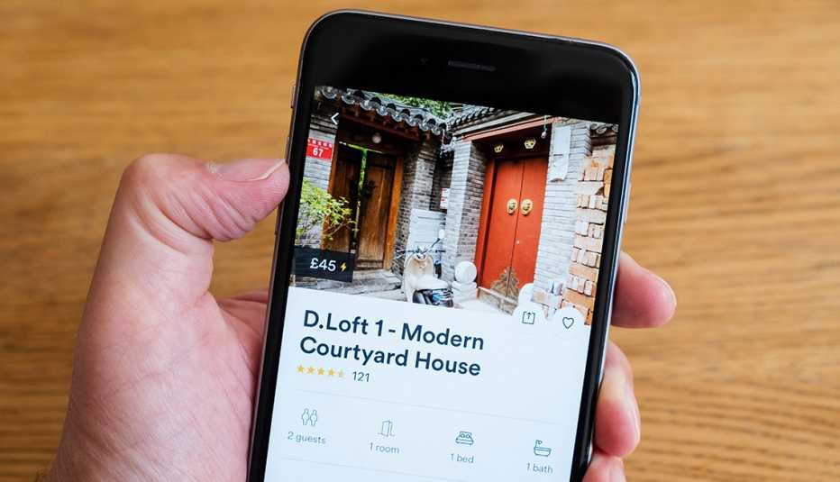 Mano sostiene un teléfono móvil con la aplicación Airbnb con una propiedad en Beijing, China