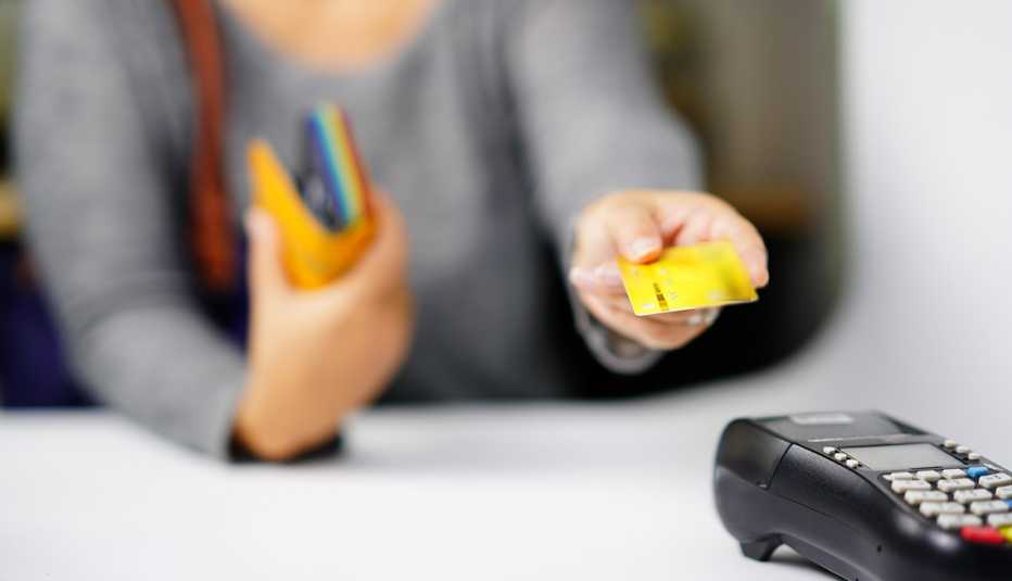 Mujer con una tarjeta de regalo frente a un datáfono.