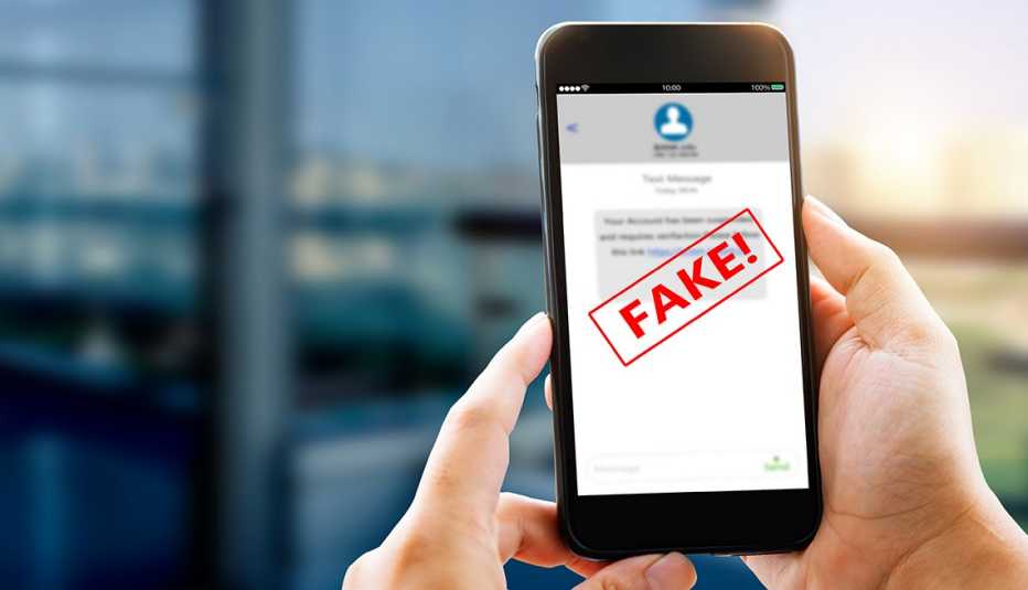Manos sostienen un teléfono móvil con una pantalla y una señal de alerta que dice falso