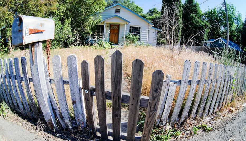 Casa con apariencia de abandono rodeada por una reja de madera