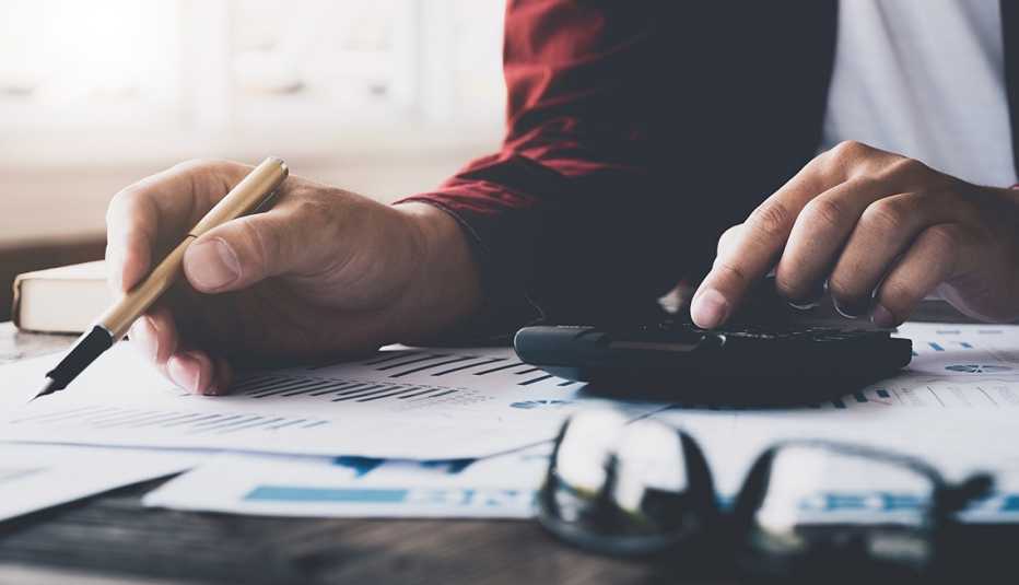 Manos de una persona sobre una calculadora y formularios.