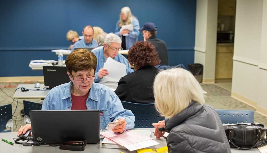 Voluntarios de AARP Foundation frente a sus computadoras atendiendo a personas mayores. 
