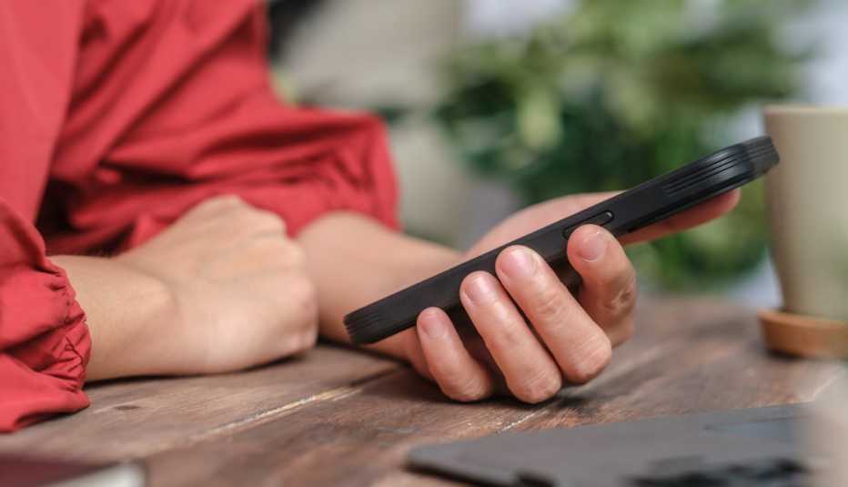 Mujer pone las manos sobre una mesa y sostiene un teléfono