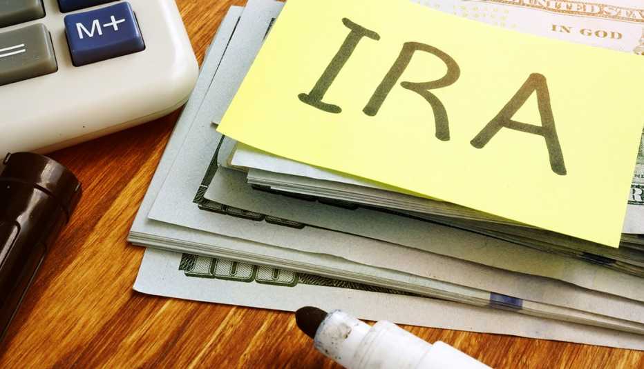 Papel con la palabra en inglés IRA, sobre varios dólares y una calculadora al lado.
