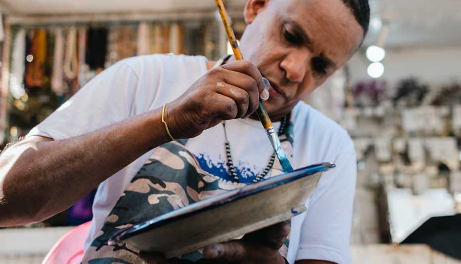 Artista pinta una vasija de cerámica en una tienda Artista pinta una vasija de cerámica en una tienda