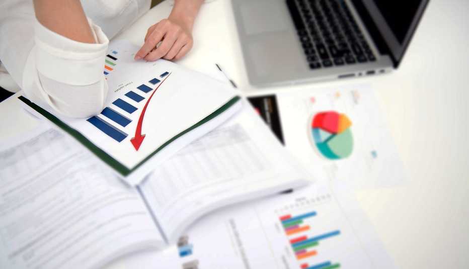 Mujer en su escritorio analizando cuadros de finanzas
