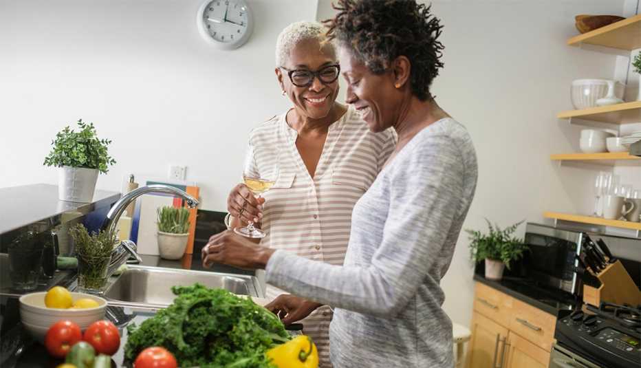 two women smiling in a kitchen, preparing a meal