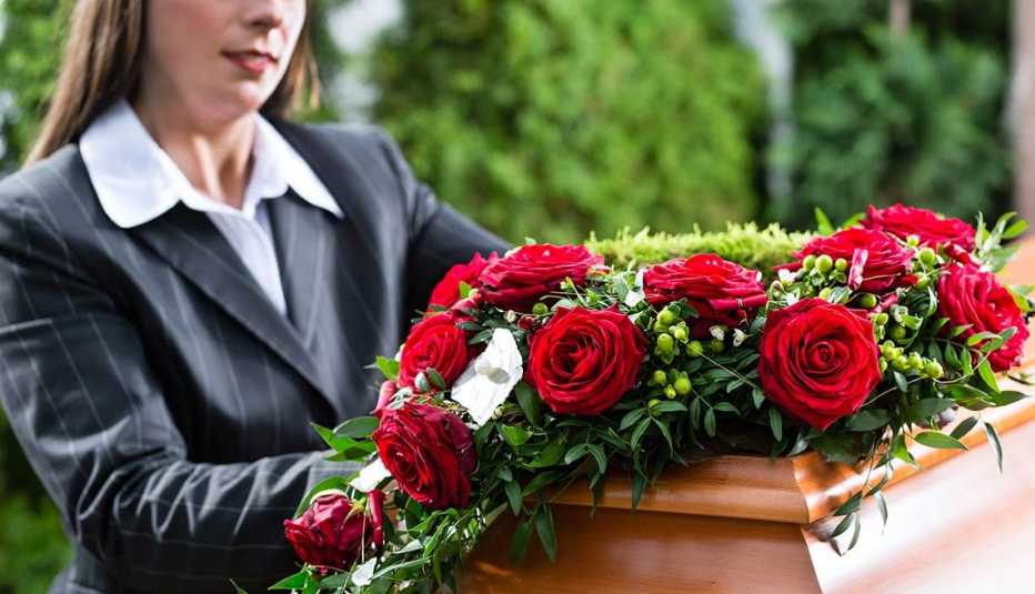 Mujer frente a un ataud con ramo de rosas encima   - Becas universitarias inusuales
