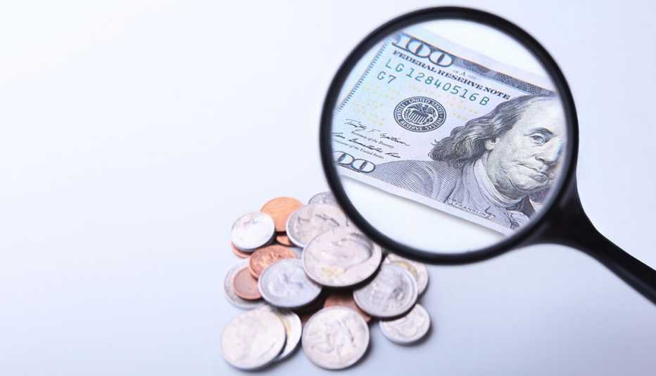 Monedas y un billete de 100 dólares visto a través de una lupa Monedas y un billete de 100 dólares visto a través de una lupa